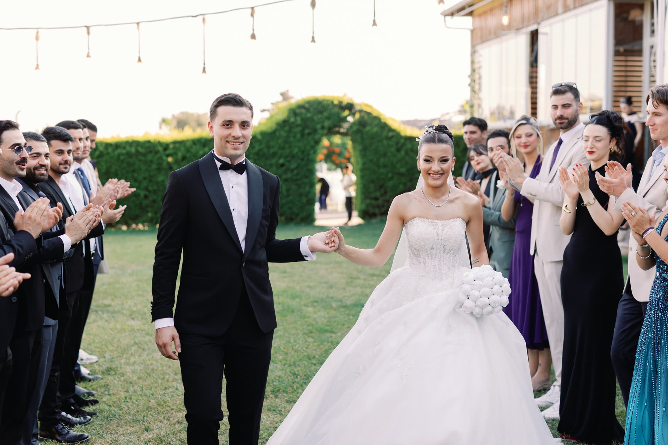 Alkışlayan davetlilerin arasından el ele geçen gelin ve damat