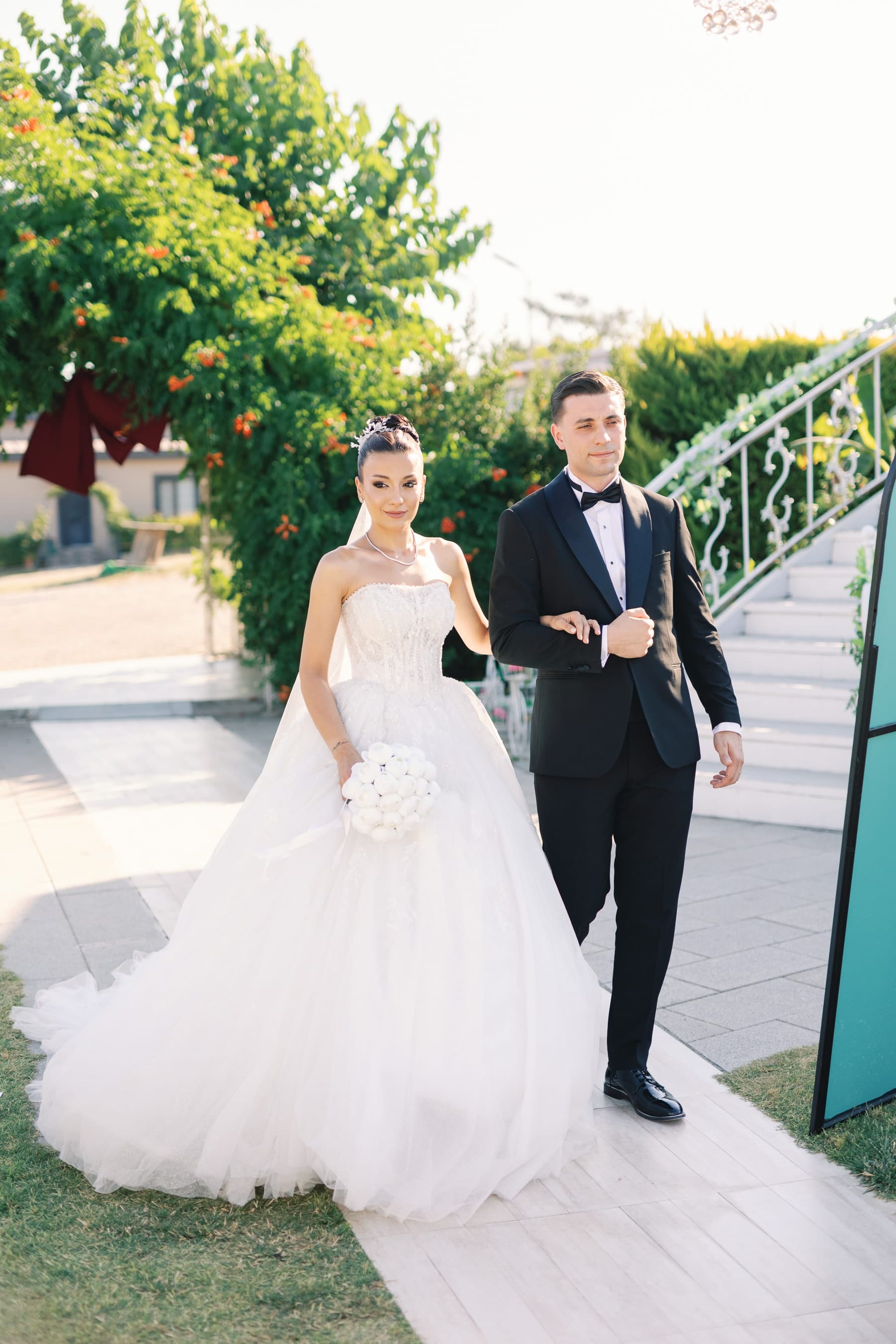 Çit tünelinin içinden yürüyen gelin ve damat — siyah-beyaz kare